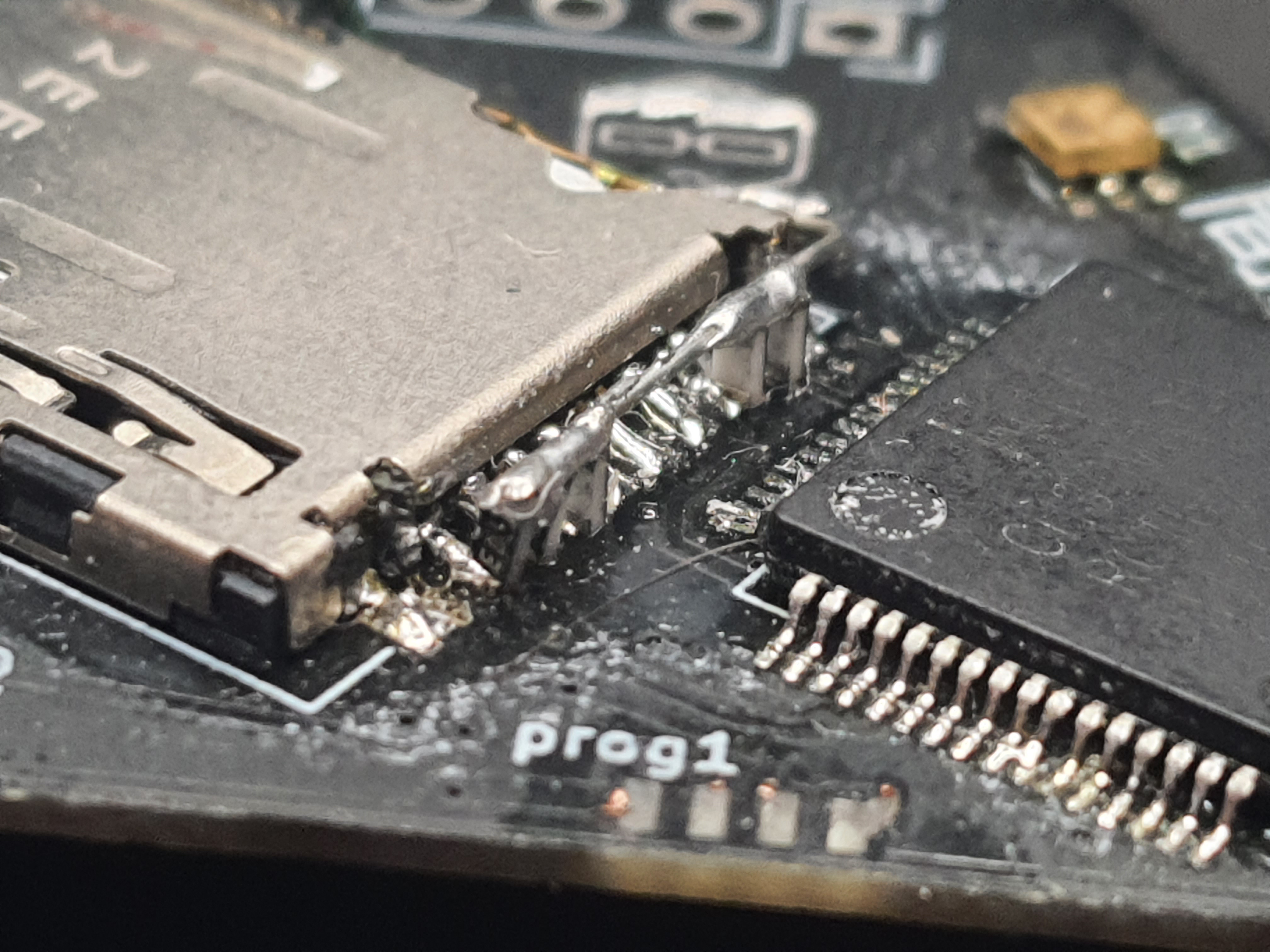 Close-up of a populated circuit board showing a bodge where SMD resistors are soldered to the board upright (long side vertical) on the pads of a SD card slot