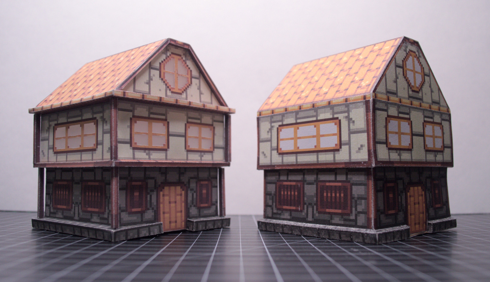 photo of the same
papercraft house as above, with another house beside it with the same
general design as the one above, but with more complex geometry, like
additional rims and columns. the old house (from above) is to the right
with the new one to the left