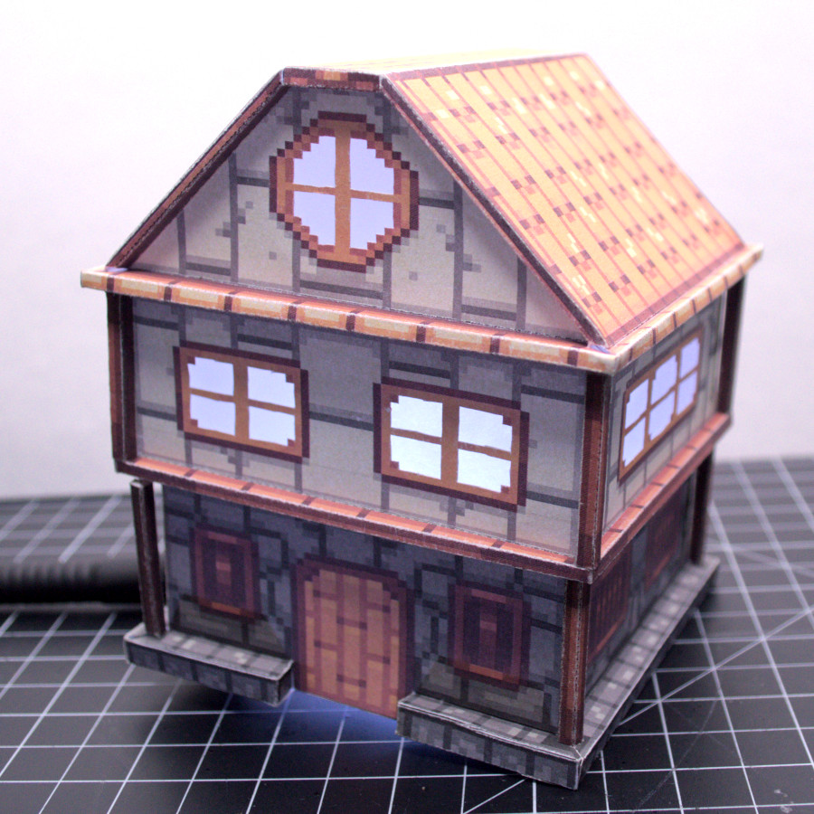 photo
of a little papercraft house in a sort of Tudor Revival style, with
a stone first floor, wooden door, and stucco second floor with wooden
beams. It is textured in a pixel-art style. There are some columns at
each vertical edge, and a rim around the house at the boundary between
each floor. Very blocky.